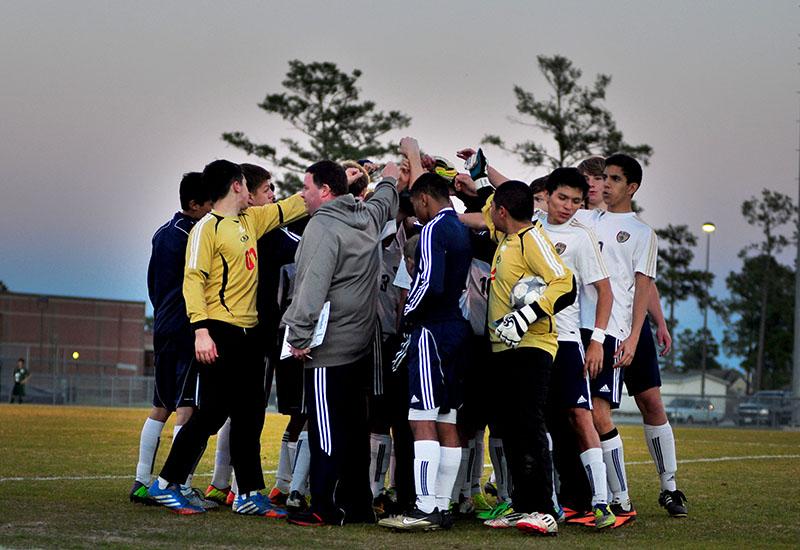 The varsity soccer team yells a chant before their first game.
