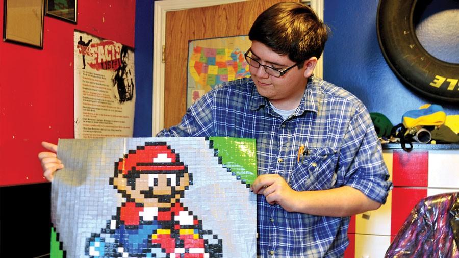 Senior Christian Carr displays his piece of duct tape art which portrays the character Mario, one of many in his collection.