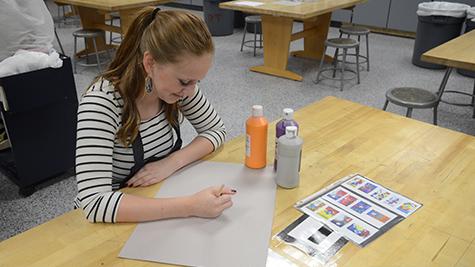 Meliya Leavitt sketches an outline for her artwork before painting it in. 