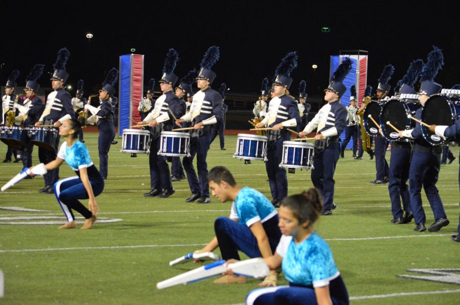 The colorguard, drumline, and band preform their show at a football game.