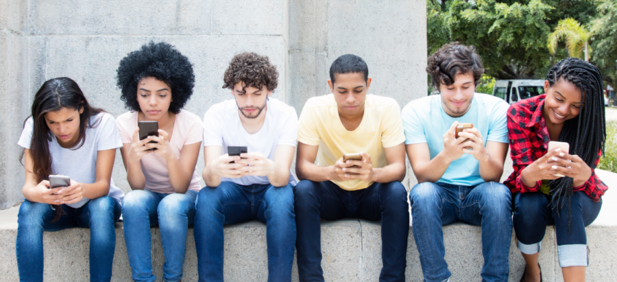 A group of students distracted on their phones outside of a school.