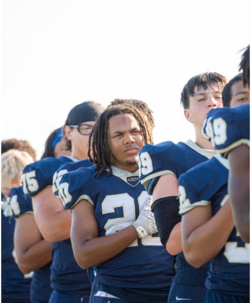 Away from the home field, sophomore Asher Mitchell stands as the National Anthem is played before KC comes away with a second district win against Willis. 